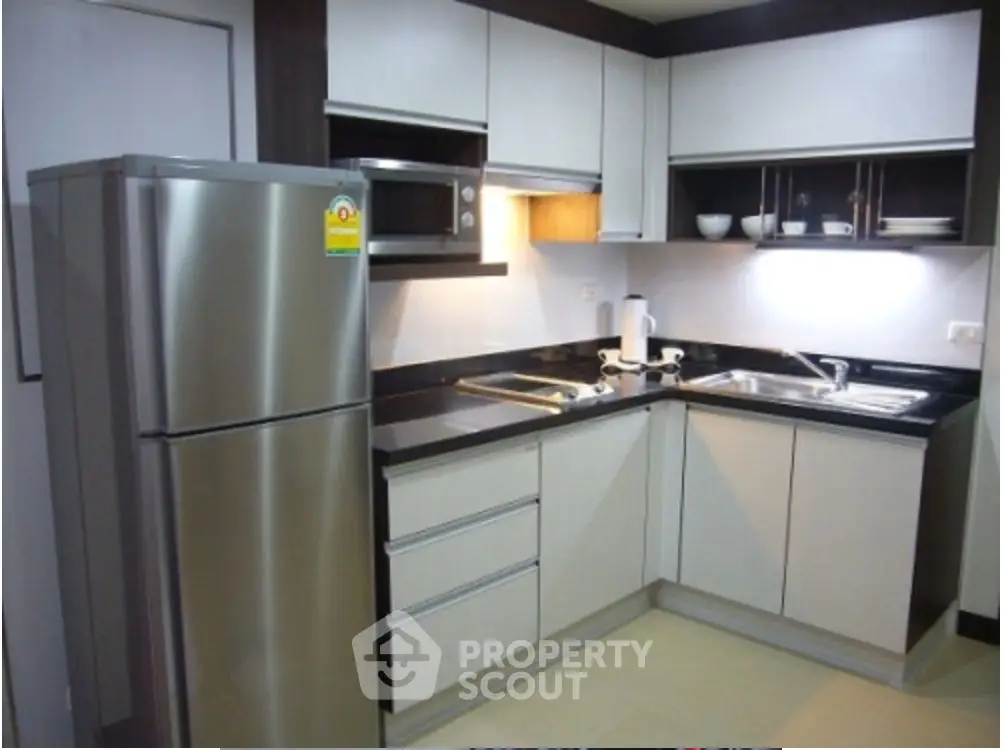 Modern kitchen with stainless steel fridge and sleek cabinetry in a stylish apartment.