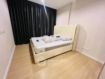 Spacious bedroom with elegant bed and floor-to-ceiling curtains, perfect for relaxation.