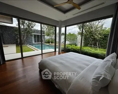 Luxurious bedroom with pool view and floor-to-ceiling windows in modern home