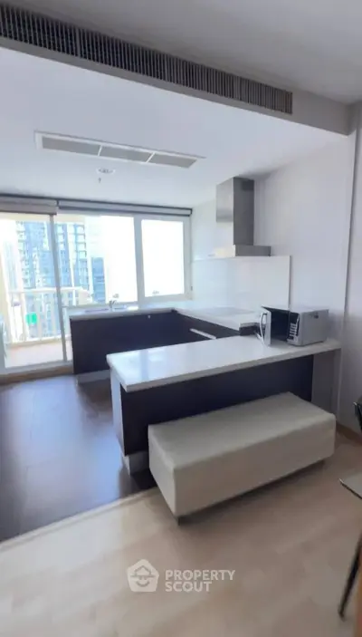 Modern kitchen with sleek design and city view, featuring a breakfast bar and built-in appliances.
