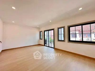Spacious empty room with large windows and wooden flooring, perfect for customization.