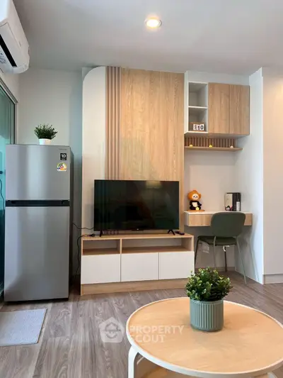 Modern living room with sleek TV unit, stylish desk, and cozy decor in a contemporary apartment.