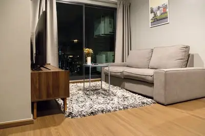 Modern living room with cozy sofa and city view through large window.