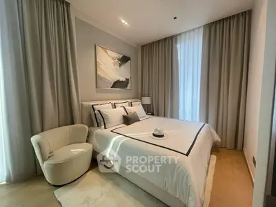 Elegant bedroom with modern decor and natural light, featuring a cozy armchair and stylish bedding.