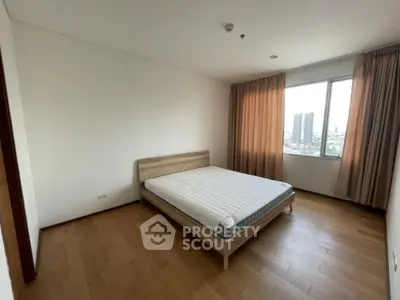 Spacious bedroom with city view and wooden flooring in modern apartment