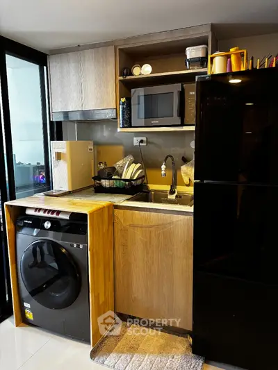 Modern compact kitchen with washing machine and microwave in stylish apartment