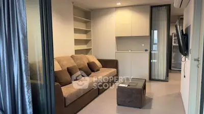 Modern living room with cozy brown sofa, glass coffee table, and built-in shelves in a stylish apartment.