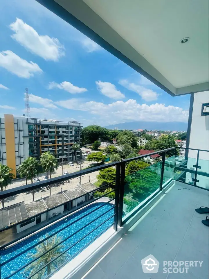 Stunning balcony view overlooking a modern cityscape and pool, perfect for relaxation.