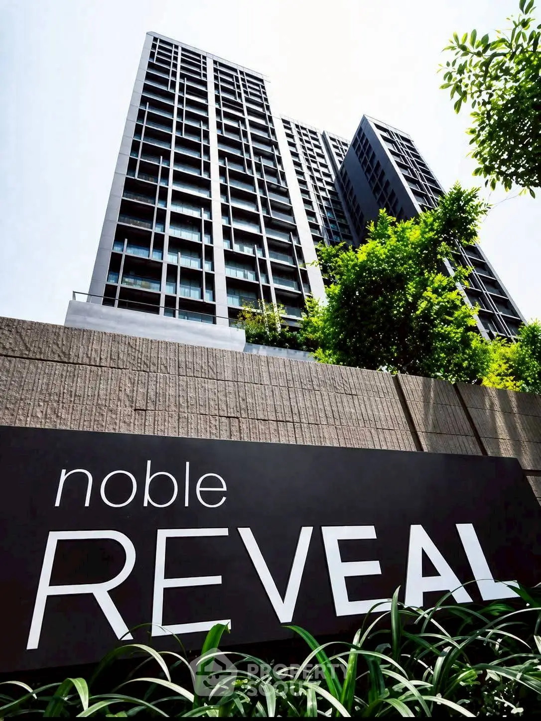 Modern high-rise building with sleek architecture and lush greenery at Noble Reveal.