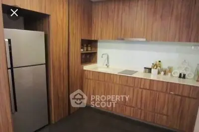 Modern kitchen with sleek wooden cabinetry and stainless steel fridge