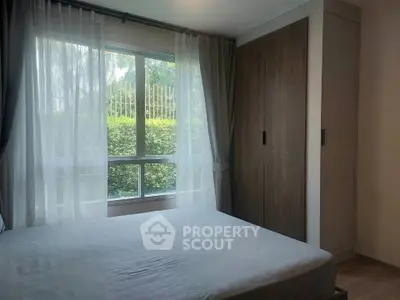 Cozy bedroom with large window and built-in wardrobe, offering serene garden views.