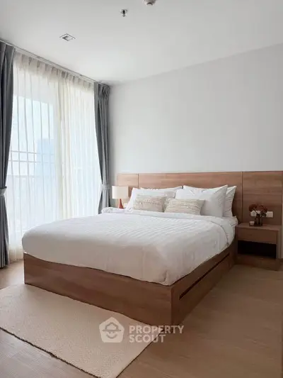 Spacious bedroom with modern wooden bed and large window for natural light.