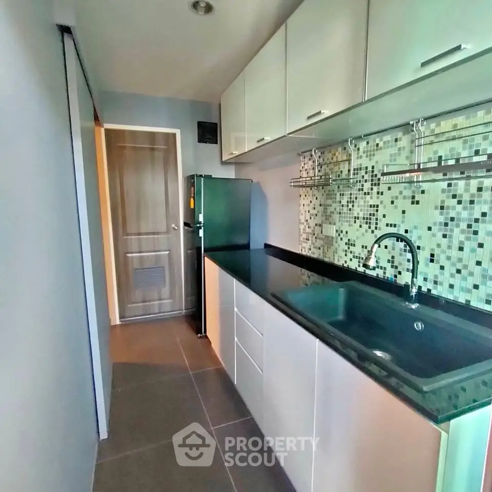 Modern kitchen with sleek cabinetry and mosaic backsplash in a stylish apartment.