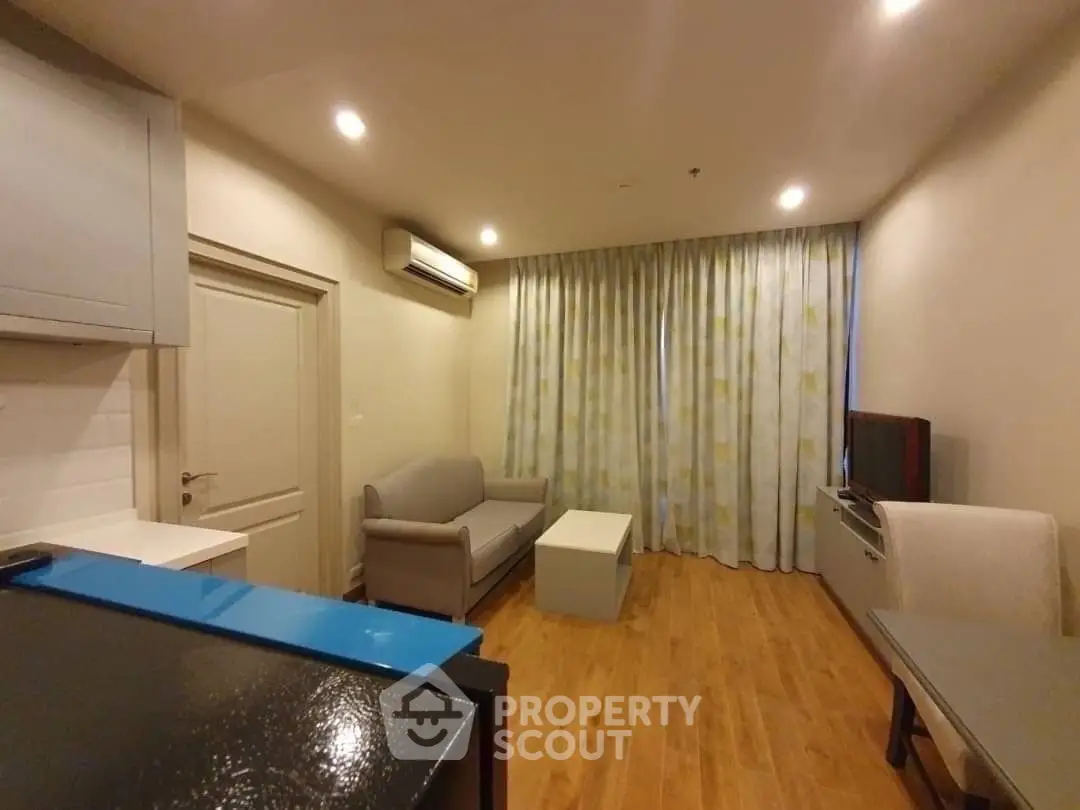 Cozy living room with modern decor and wooden flooring, featuring a comfortable sofa and flat-screen TV.