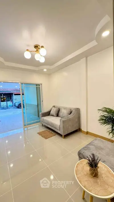 Modern living room with elegant lighting and cozy sofa, featuring a sliding glass door to the outside.