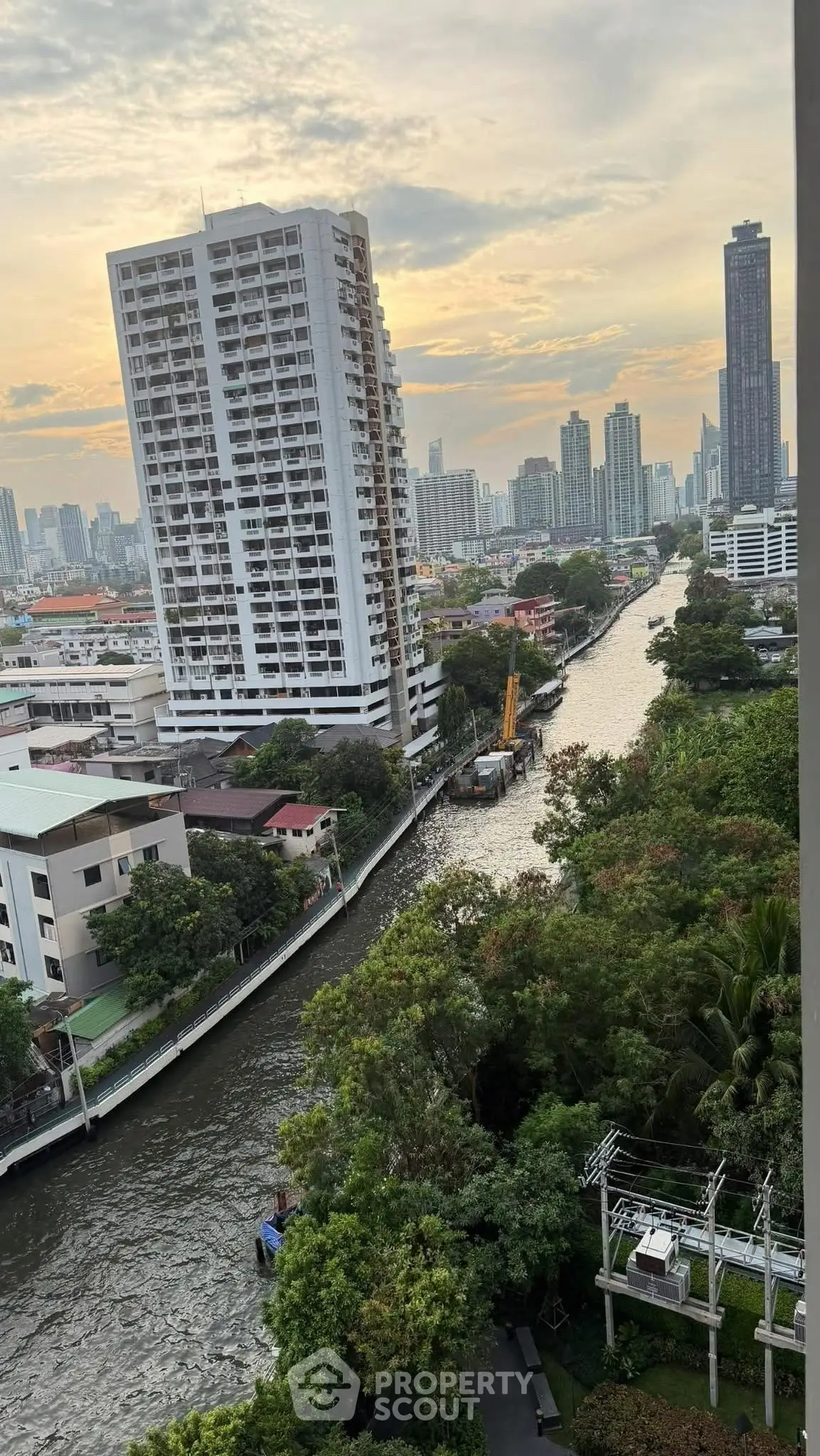 Stunning cityscape view with river and modern high-rise buildings at sunset.