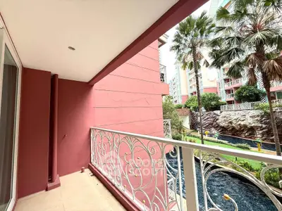 Charming balcony with ornate railing overlooking lush garden and pool in modern residential complex.