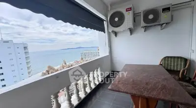 Stunning ocean view from a balcony with seating area and air conditioning units.