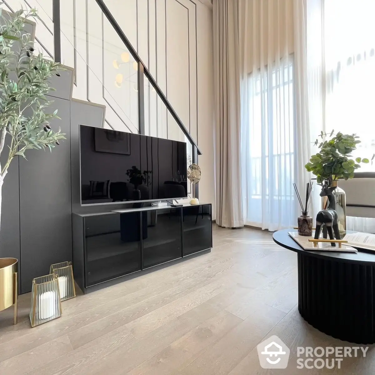 Elegant living room with modern design, featuring sleek entertainment unit, large windows with sheer curtains, and chic decor.