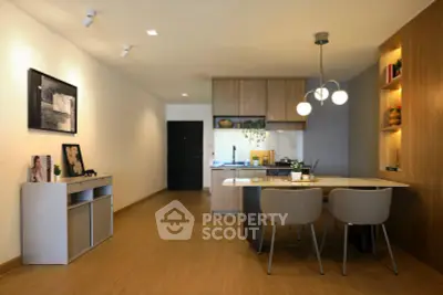 Modern open-layout kitchen and dining area with stylish lighting and wooden flooring.
