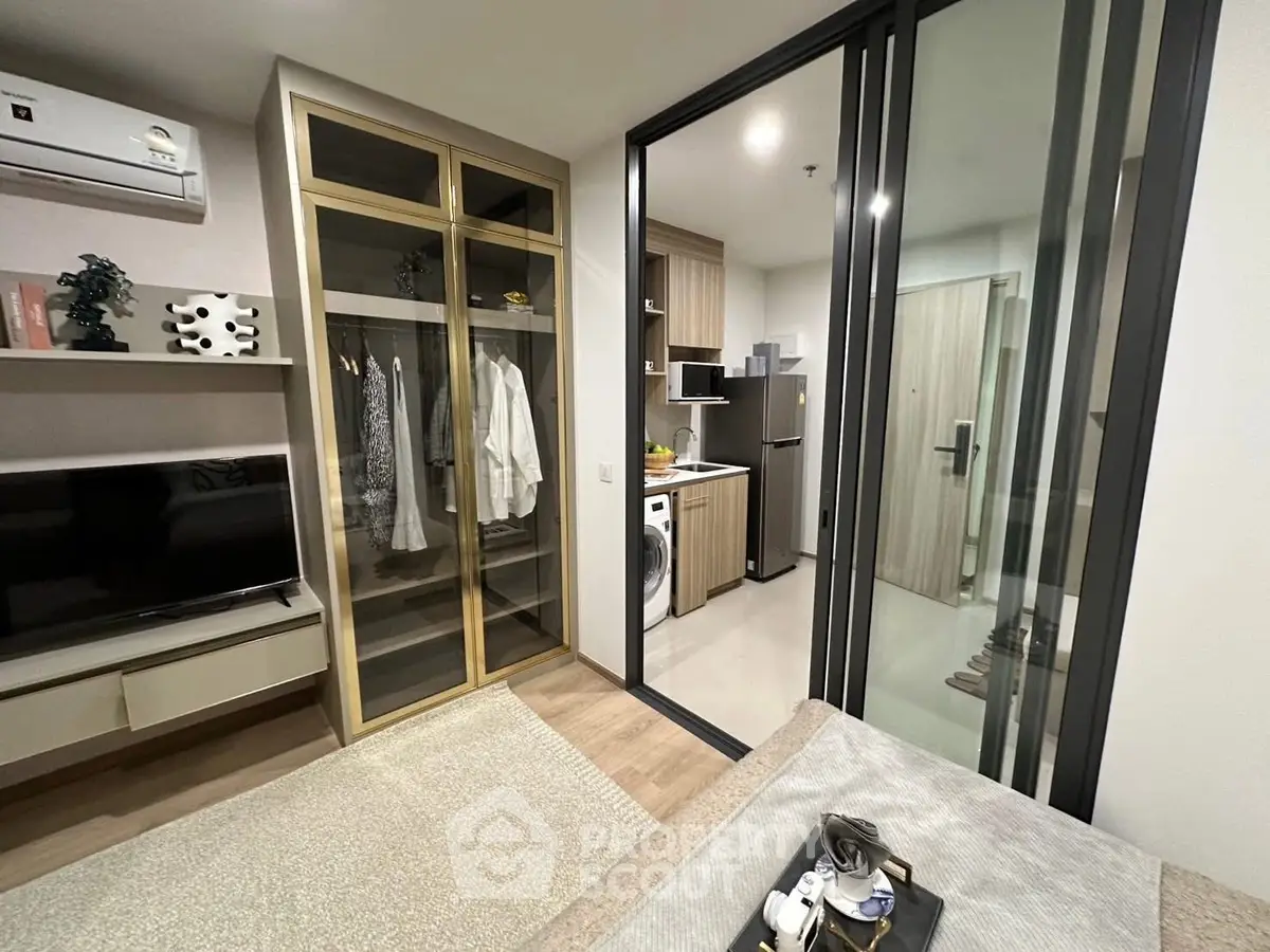 Modern apartment with open layout, featuring a cozy living area and sleek kitchen with glass partition.
