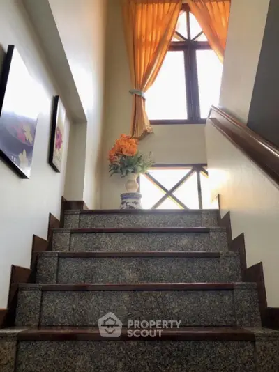 Elegant staircase with polished granite steps, natural light from window, and tasteful decor, enhancing the home's luxurious appeal.