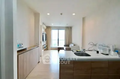 Spacious open-plan living room with modern kitchen and large window view.