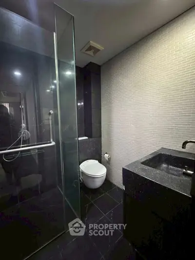 Modern bathroom with sleek black tiles and glass shower enclosure
