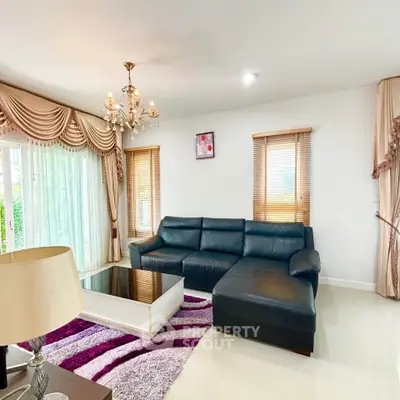 Elegant living room with luxurious chandelier and stylish leather sofa in a bright, airy space.