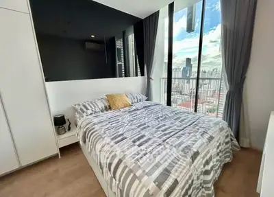 Modern bedroom with city view, floor-to-ceiling windows, and stylish decor in urban apartment.