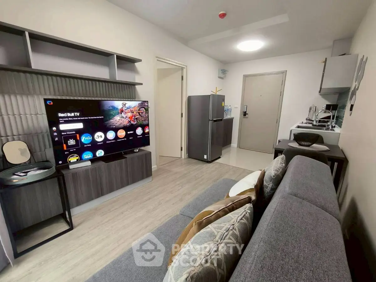 Modern living room with sleek furniture and smart TV, open kitchen layout, and stylish decor.