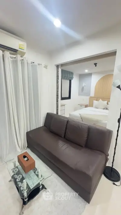 Modern living room with cozy sofa and view into stylish bedroom