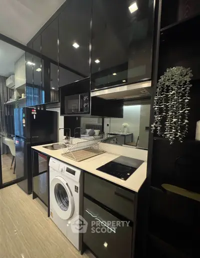 Modern kitchen with sleek black cabinets, built-in appliances, and a washing machine for efficient living.