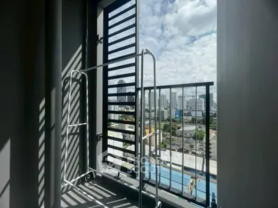 City view from a high-rise balcony with metal railing and drying rack.