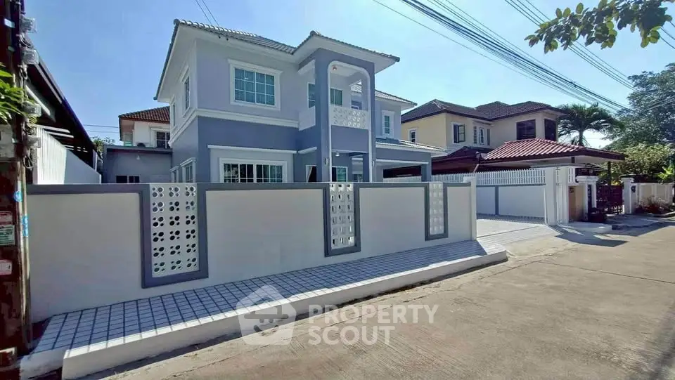 Modern two-story house with stylish facade and gated entrance in a suburban neighborhood.