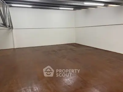Spacious empty storage room with polished wooden floors and bright lighting.