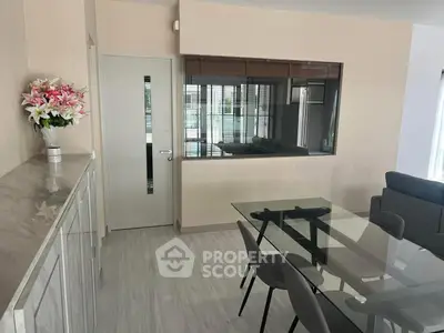 Modern dining area with glass table and stylish chairs in open layout apartment.