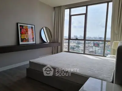Spacious bedroom with city view and modern decor in high-rise apartment.