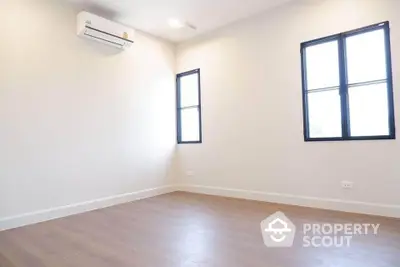 Spacious and well-lit empty room with polished wooden flooring, crisp white walls, and two large windows providing ample natural light, perfect for custom interior design.