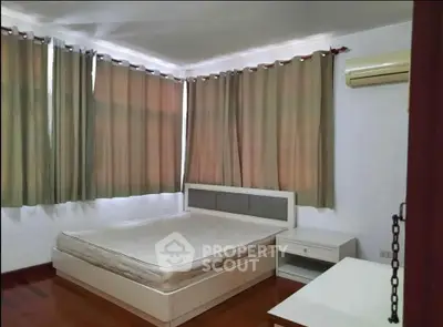 Spacious bedroom with large windows and air conditioning, perfect for comfort and relaxation.