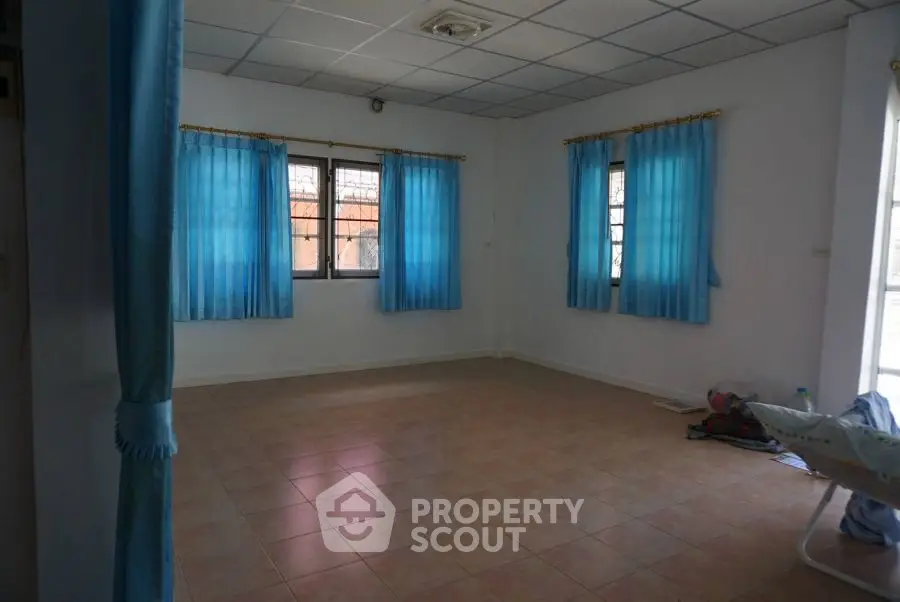 Spacious empty room with tiled floor and blue curtains, ideal for customization.