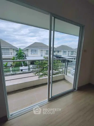 Spacious balcony with sliding glass doors offering a serene view of suburban homes.