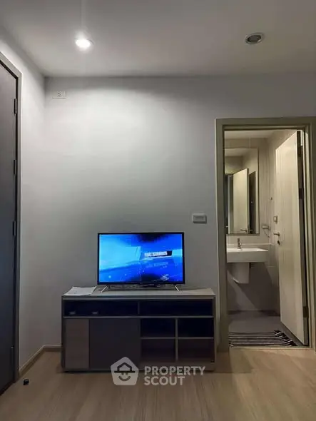 Modern living room with TV and view into a sleek bathroom