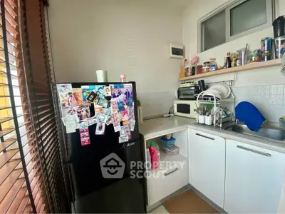 Cozy kitchen with modern appliances and ample storage space, featuring a sleek black fridge and natural light.