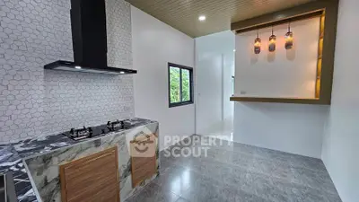 Modern kitchen with sleek gas stove and stylish lighting in contemporary home.