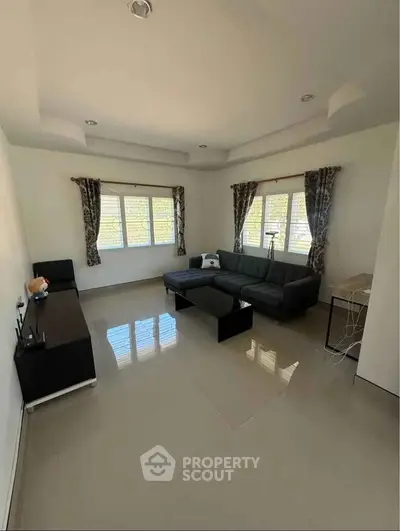 Spacious living room with modern sofa and large windows offering natural light.