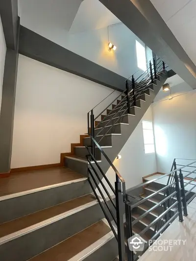 Modern staircase with sleek metal railings and wooden steps in a bright interior space.