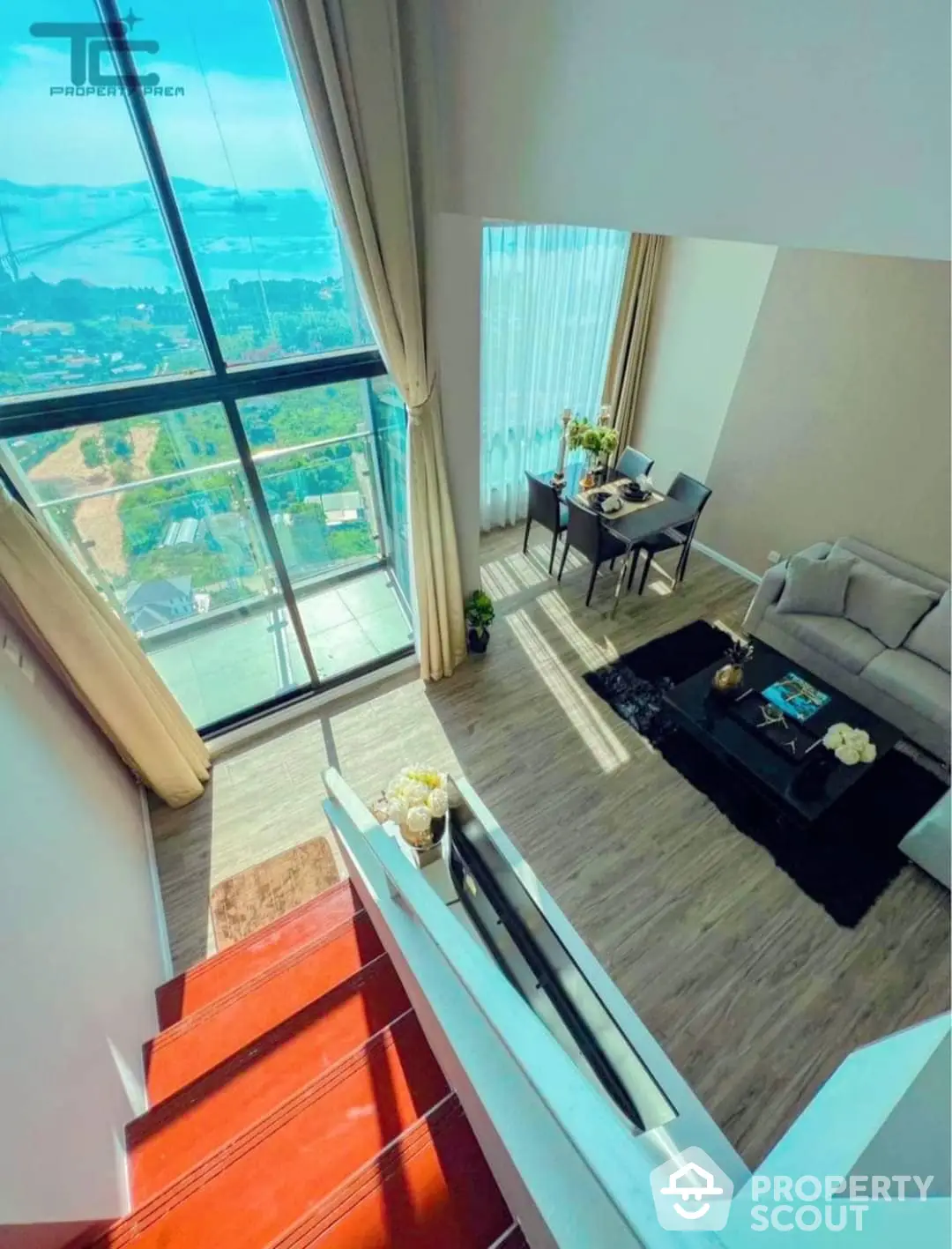 Luxurious high-ceiling living room with floor-to-ceiling windows offering panoramic views, elegantly furnished with modern decor and a touch of vibrant red stairs.