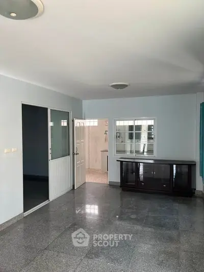 Spacious living room with sleek tiled flooring and ample natural light, perfect for modern living.