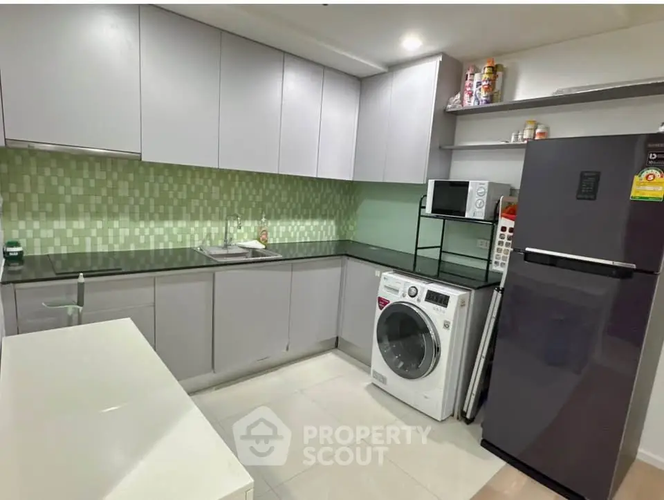 Modern kitchen with sleek cabinets, washing machine, and stylish backsplash